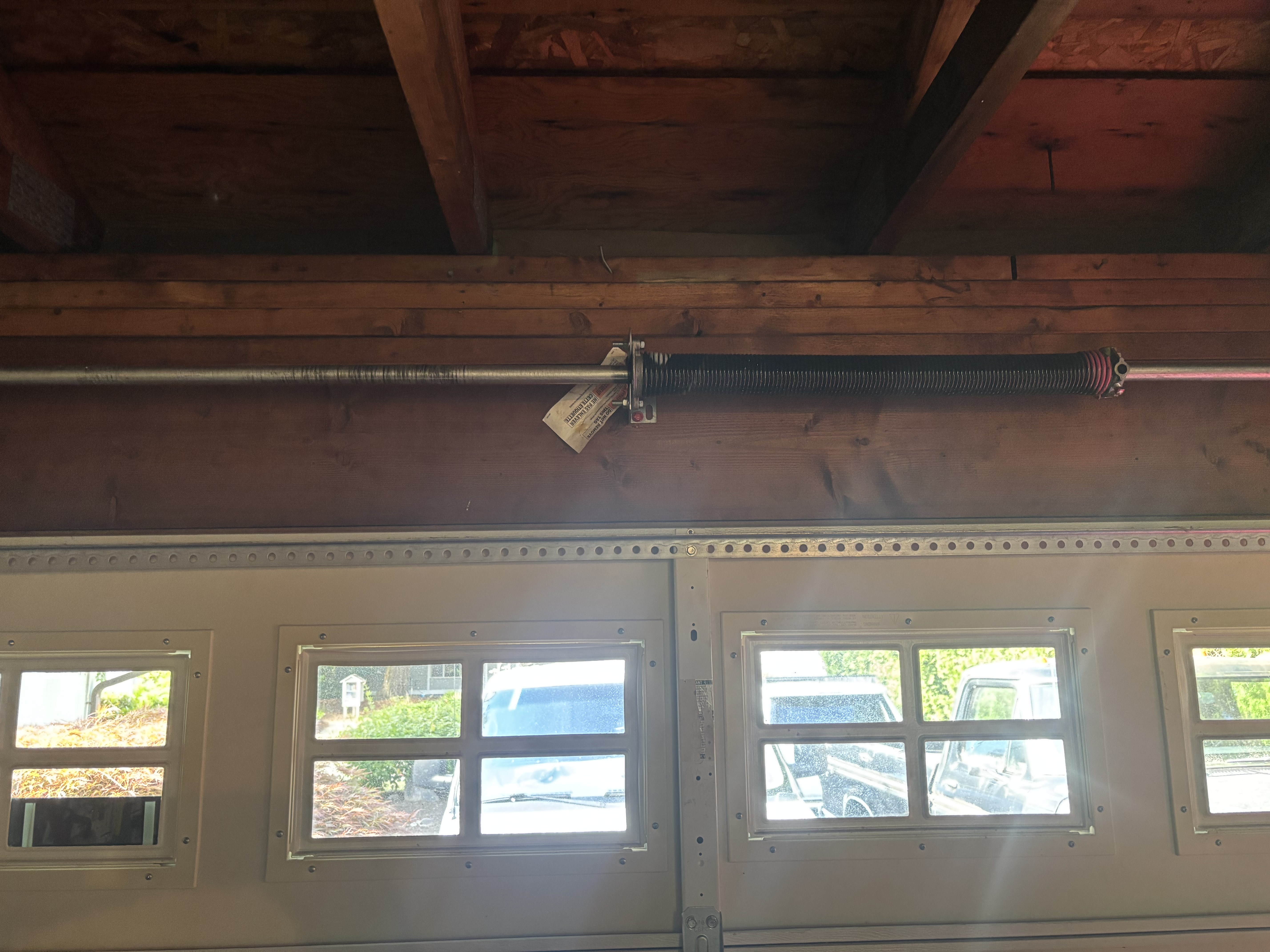 Torsion spring around a horizontal shaft mounted above a sectional garage door