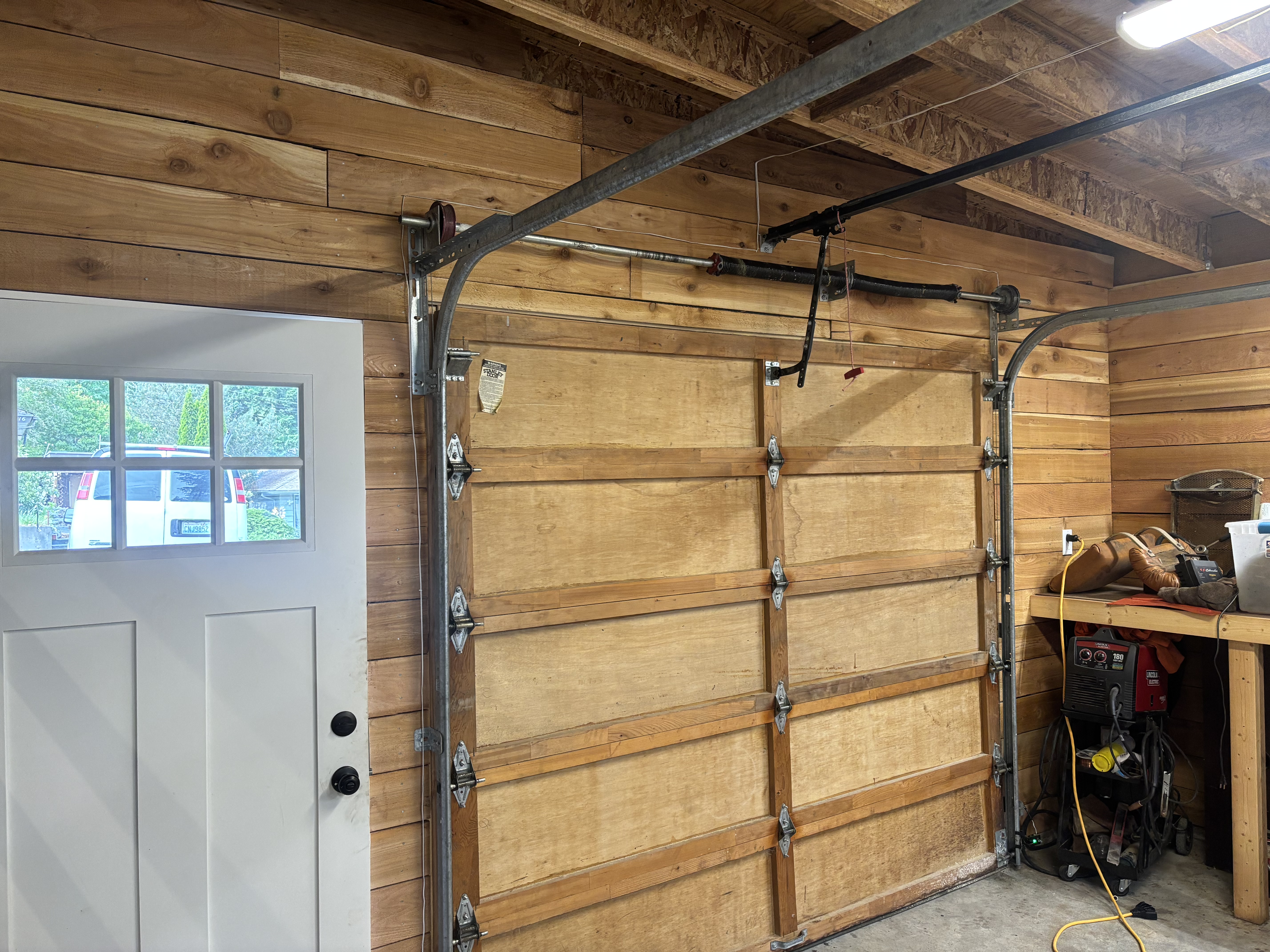 Interior of a wooden sectional door showing hinges, side tracks, spring shaft and opener rail