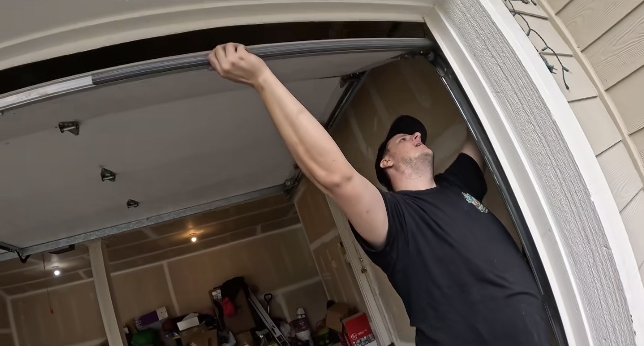 Wesley Zietz reaching up to work on the garage door track at a residential garage opening.