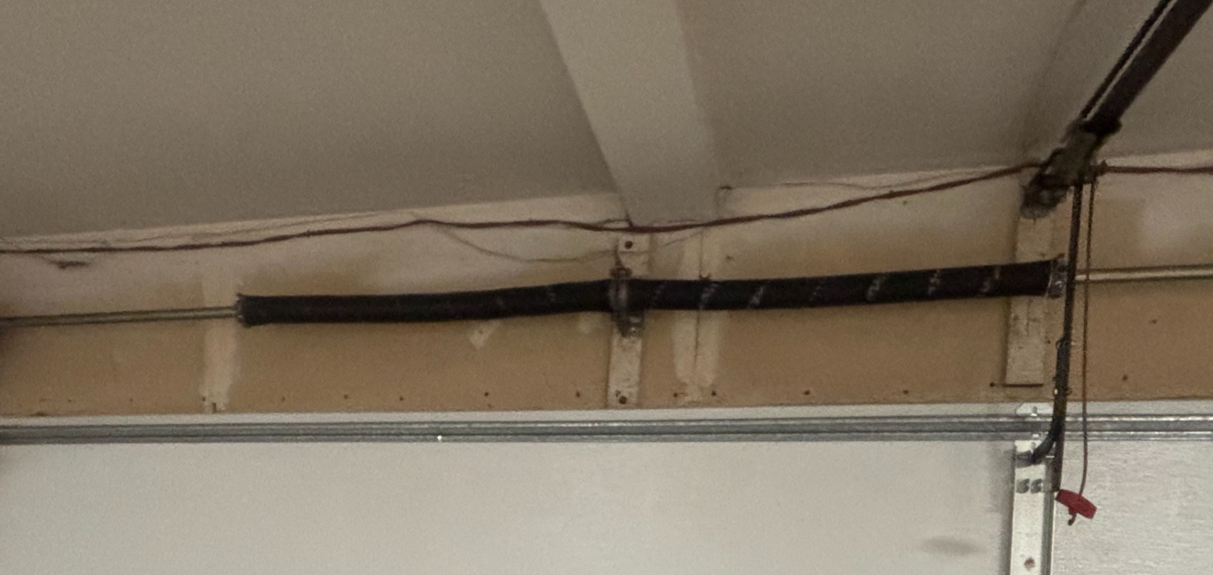Torsion spring shaft and surrounding cable and track area above a sectional garage door