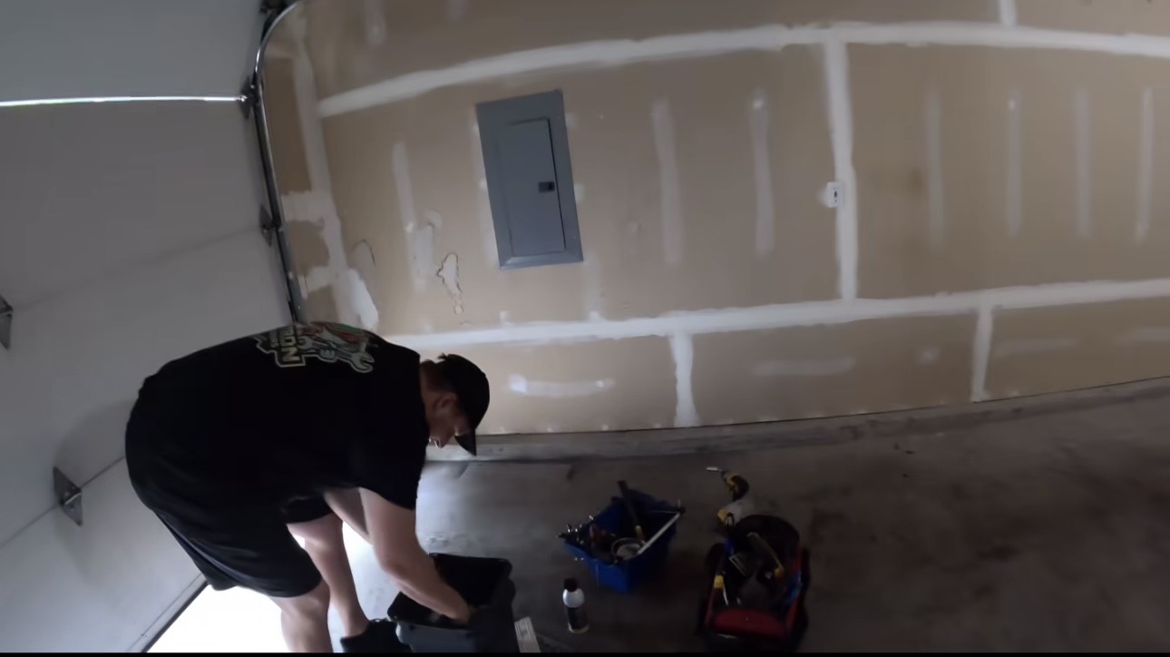Wesley Zietz gathering tools beside a residential garage door.