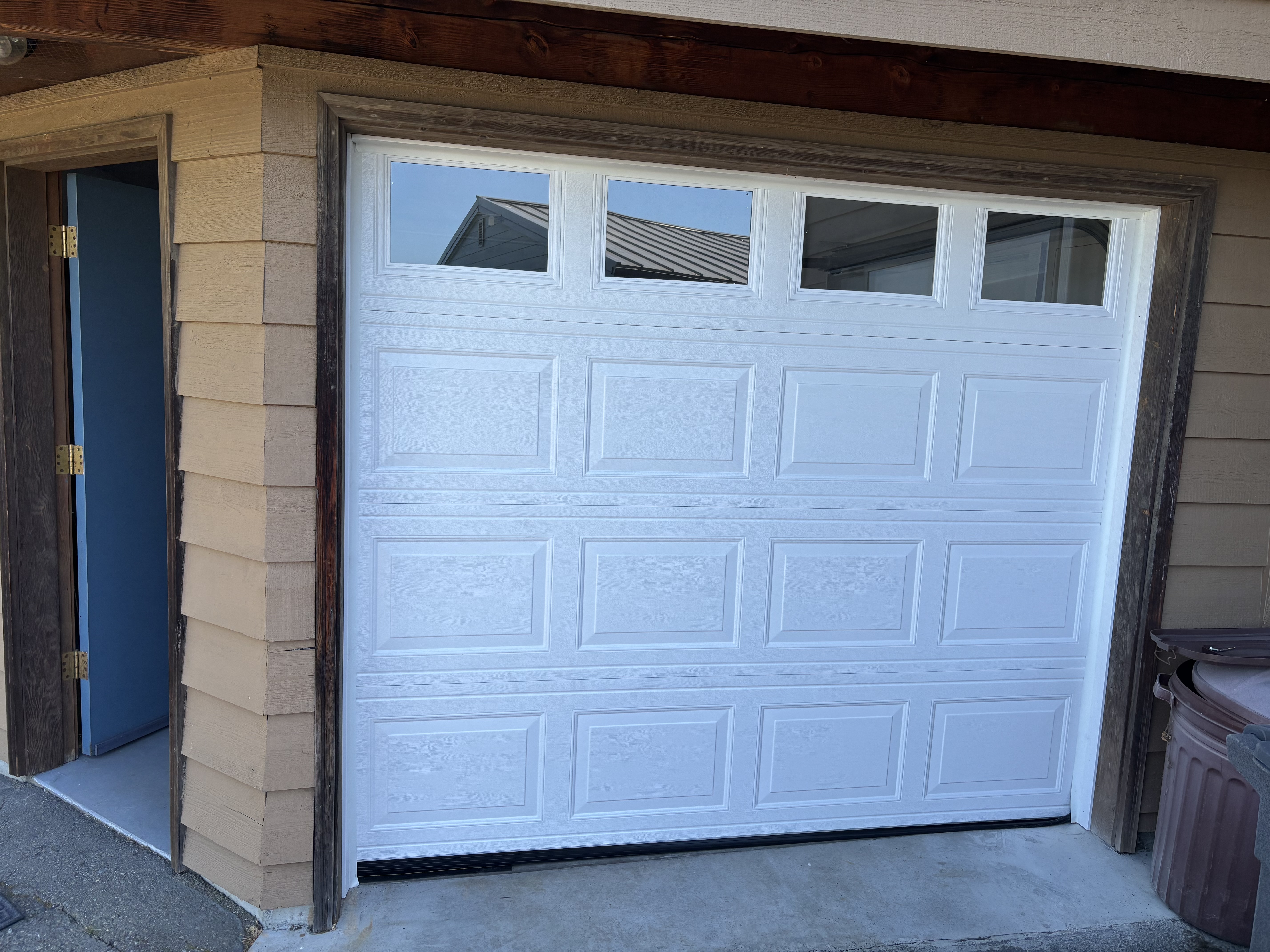 White raised-panel garage door with a row of windows on a residential garage