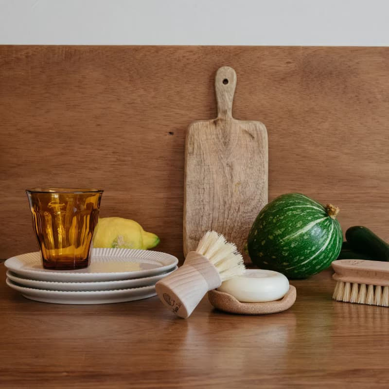 Brosse vaisselle en bois, savon solide, planche et vaisselle en grès disposés avec légumes de saison – kit zéro déchet Maison Julio × Andrée Jardin Les Jolies Emplettes