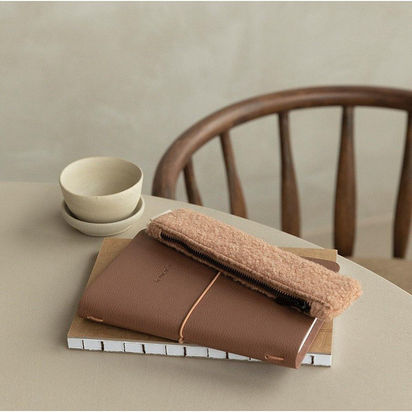 agenda et trousse posés sur une table avec jolie céramique et chaise en bois