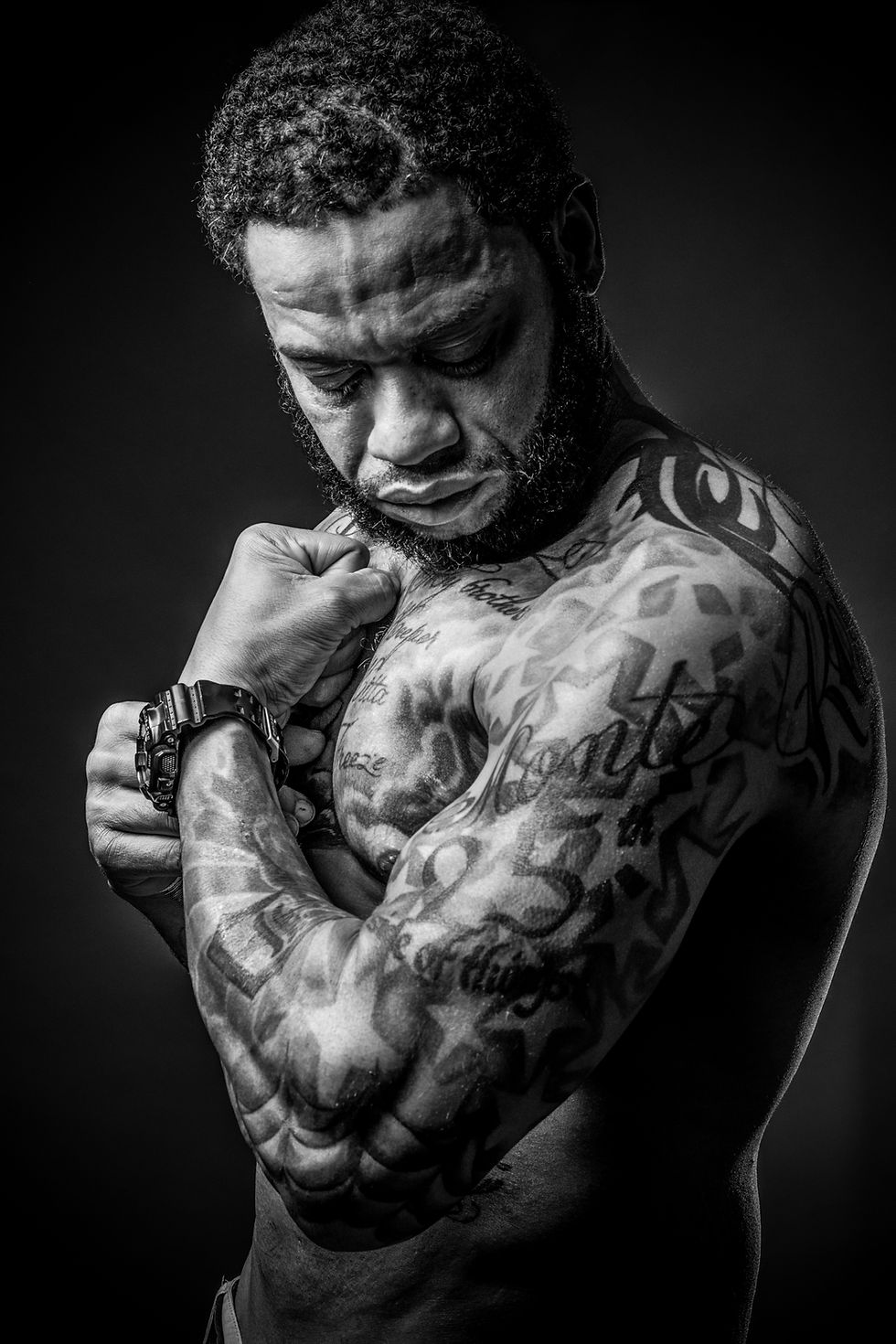 Eye-level view of a man standing against a textured brick wall with soft natural light