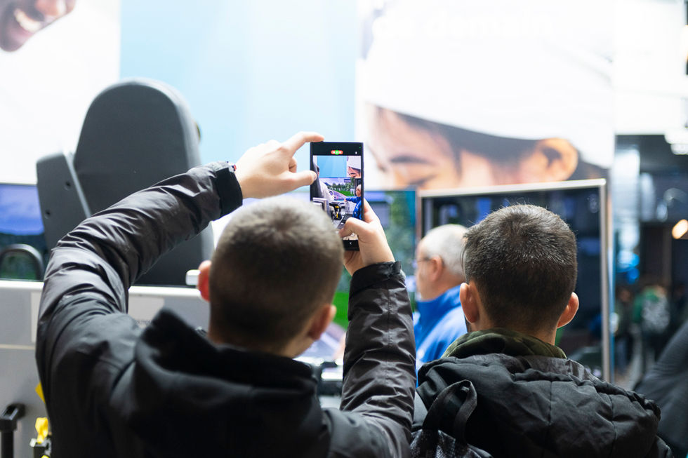 Visiteur documentant une démo produit au téléphone lors d'un salon professionnel à Paris