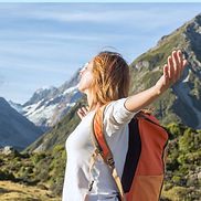 Mujer respira hondo y abre los brazos en la montaña