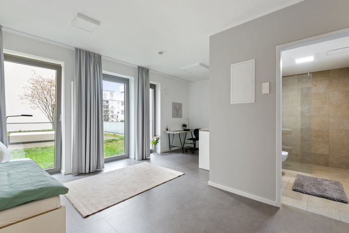 Studio 152 Wiesbaden - möbliertes Apartment mit Bett, Fensterfront und Blick ins Bad