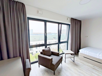 Urban Base Living House Düsseldorf - Apartment mit bodentiefer Fensterfront, Sessel und Bett