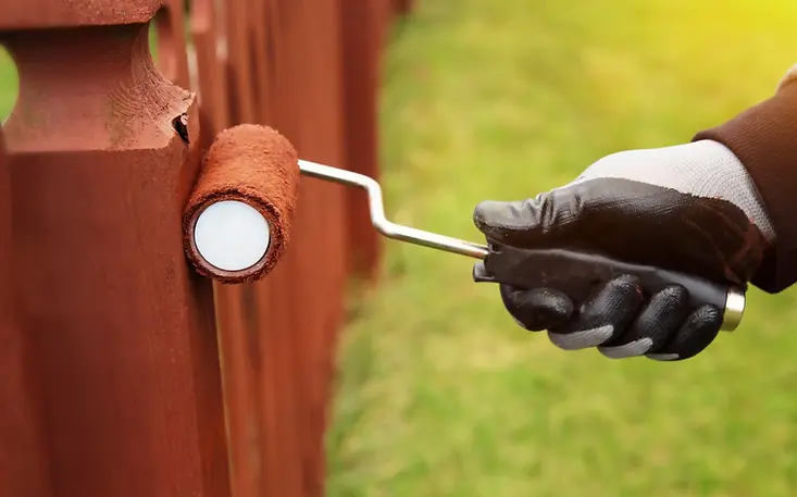 Person-painting-fence-with-roller-scaled.jpg.webp