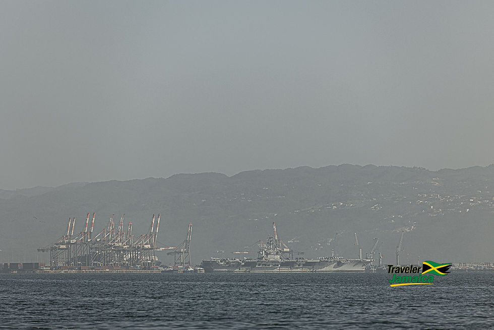 USS Nimitz visits Kingston, shrouded in a haze of Saharan dust, with cranes and mountains in the background.