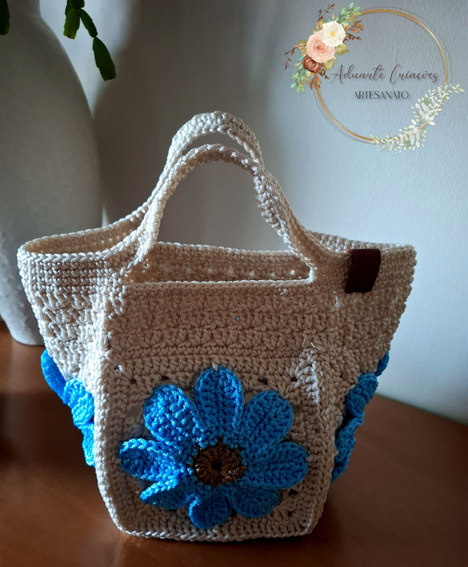 Bolsa quadrada em crochê com flores azul.