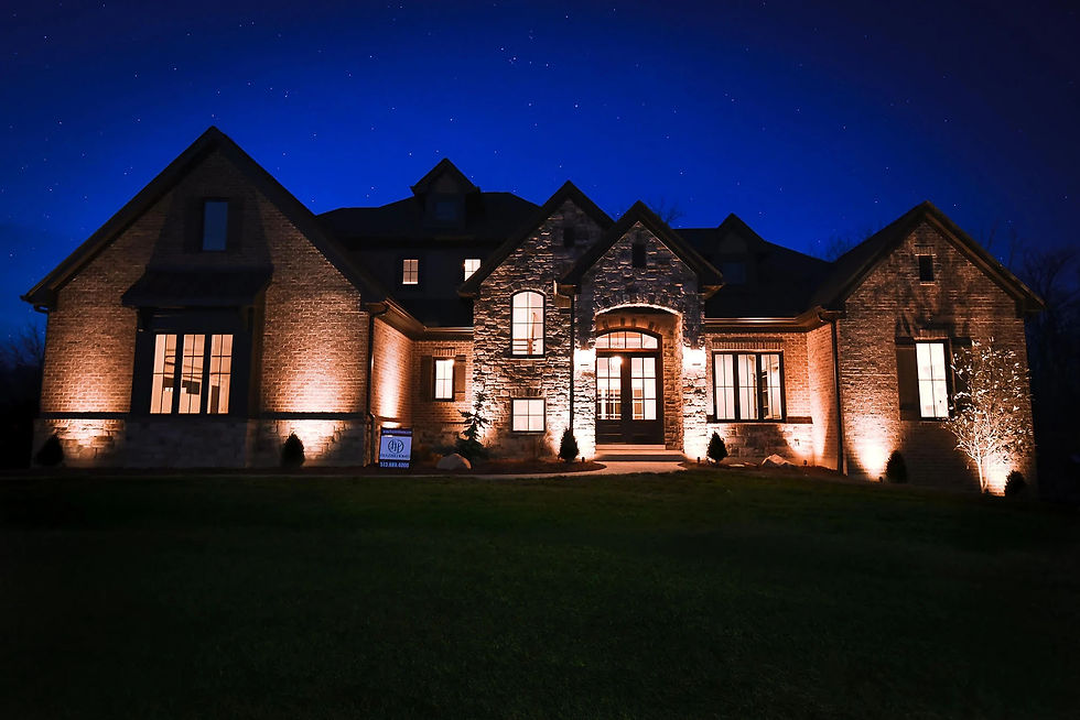Luxury custom home exterior at night with warm architectural lighting, highlighting stone and brick details by Frazier Homes in Ohio.