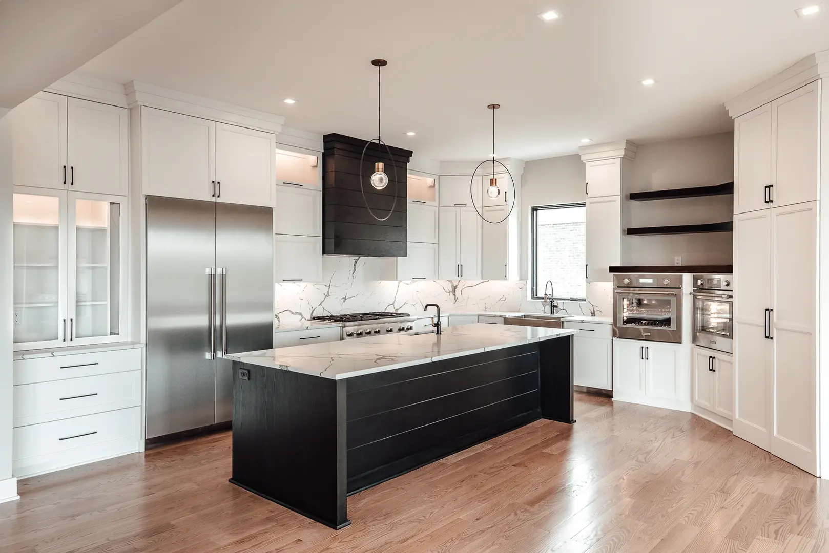 Modern luxury kitchen with black waterfall island, custom white cabinetry, stainless appliances, and contemporary lighting by Frazier Homes in Walworth Junction, Cincinnati