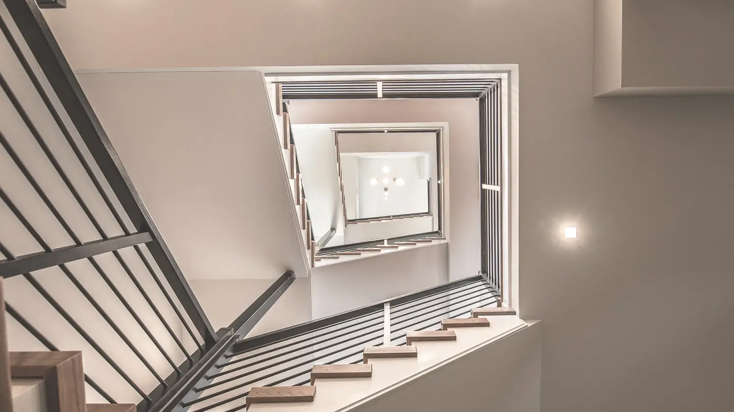 Modern multi-level staircase with steel balusters, hardwood steps, and geometric vertical design in a Walworth Junction home by Frazier Homes.