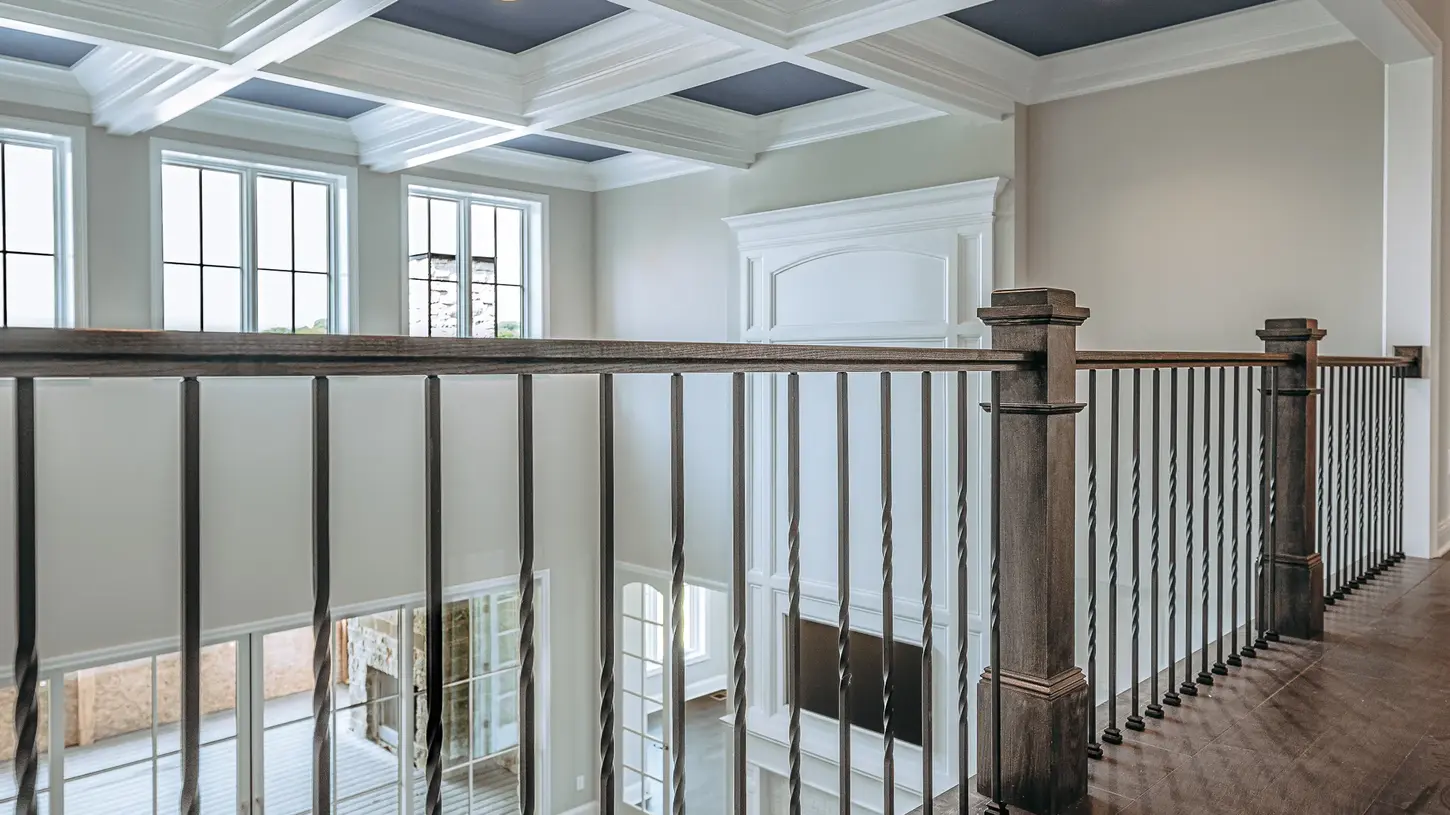 Hyde Park luxury home overlooking two-story living room with custom wood railing, twisted iron balusters, and detailed coffered ceiling by Frazier Homes.