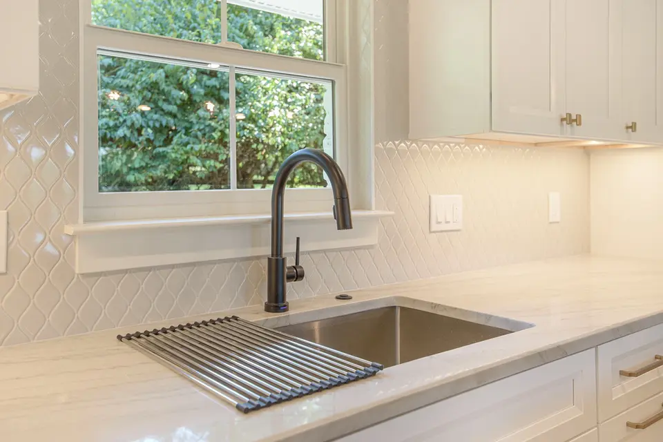 Modern kitchen sink with matte black faucet, quartz countertops, and white tile backsplash in a Montgomery Ohio luxury kitchen remodel by Frazier Homes.