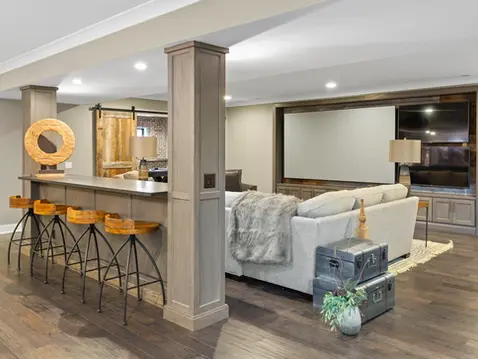 Luxury custom home entertainment space by Frazier Homes featuring a home theater, built-in bar with seating, custom millwork, and an open-concept lower level designed for entertaining and relaxation.