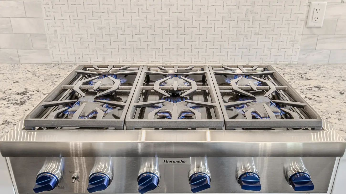 Luxury Thermador gas cooktop with blue-flame burners set into stone countertops in a custom Hyde Park kitchen by Frazier Homes.