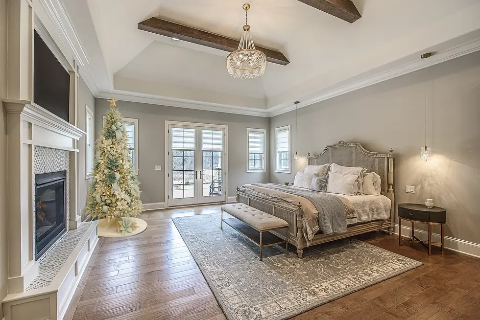 Luxury primary bedroom with vaulted ceiling, exposed beams, elegant holiday décor, fireplace, and French doors — Frazier Homes custom bedroom retreat design.