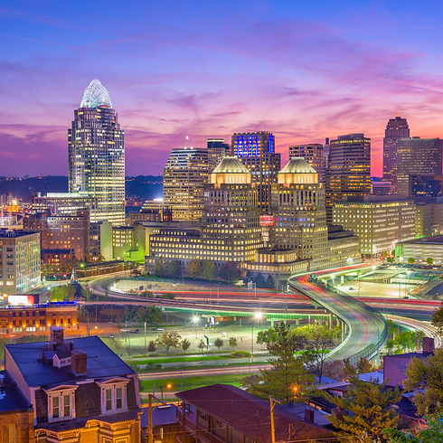 Downtown Cincinnati skyline at sunset, with city lights glowing and highways visible — illustrating the close proximity of Cincinnati to Mason for Frazier Homes’ service area.
