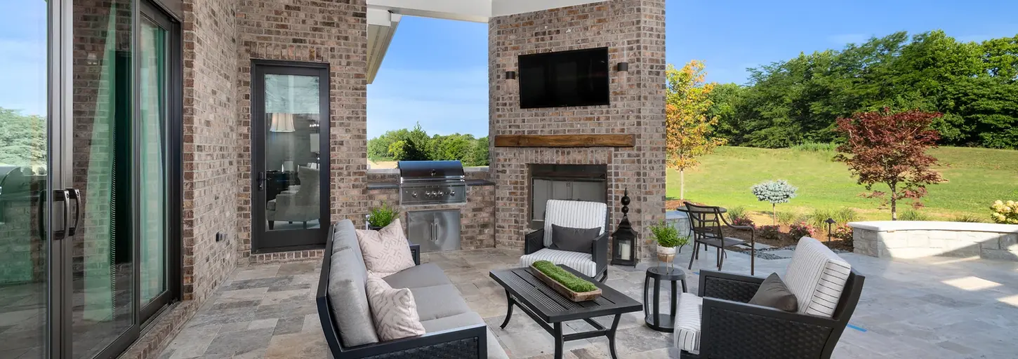 Discover outdoor living at its finest in our backyard oasis, showcasing a covered porch with an inviting outdoor fireplace and mounted TV. Experience the ultimate in relaxation and entertainment right in your own backyard.