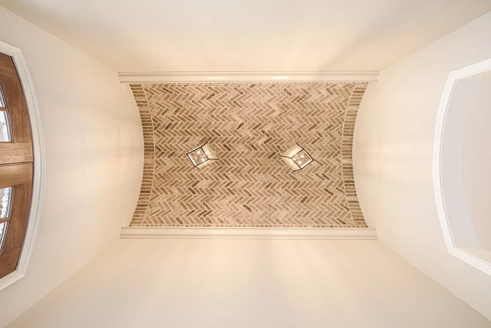 Luxurious barrel-vaulted entryway ceiling featuring herringbone brickwork, elegant trim detailing, and refined architectural lighting in a custom Frazier Homes residence.