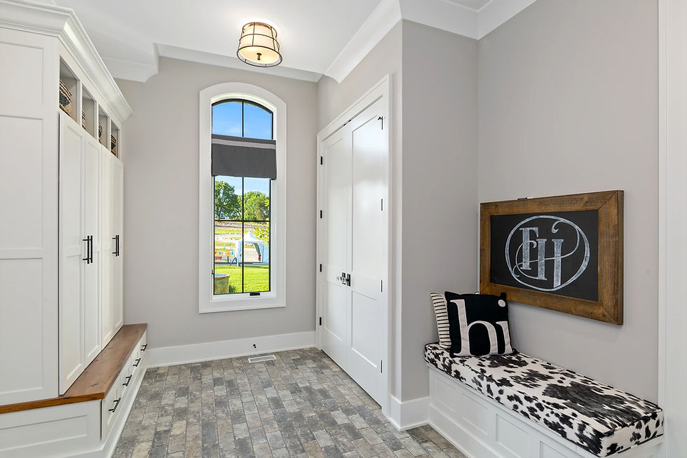 Modern mudroom with built-in storage cabinets, a cushioned bench, and wall-mounted Frazier Homes chalkboard art, designed for an organized entryway.