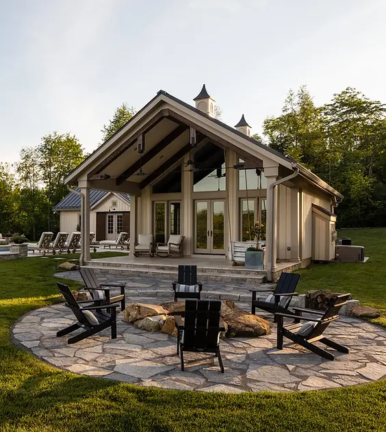 This breathtaking outdoor retreat by Frazier Homes features a beautifully designed pool house that seamlessly blends luxury and functionality. With vaulted ceilings, expansive glass doors, and warm wood accents, the pool house provides the perfect space for relaxation and entertaining. The surrounding outdoor oasis includes a stunning stone fire pit, a covered patio with a cozy fireplace, and a resort-style pool area, all nestled in a lush green landscape. Every detail reflects craftsmanship and thoughtful design, creating a timeless and inviting outdoor living experience.