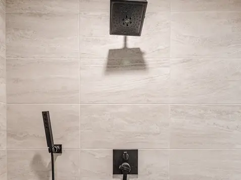 Modern walk-in shower with rainfall showerhead, matte black fixtures, and stone tile in a luxury Hamilton, Ohio remodel by Frazier Homes.