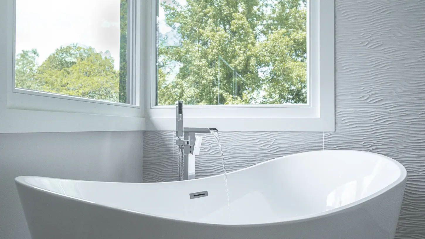 Freestanding soaking tub in luxury Montgomery, Ohio bathroom with textured wall tile and chrome fixtures by Frazier Homes.