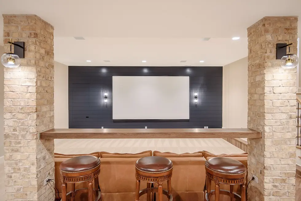 Fully custom home theater with brick columns, leather seating, and a large projection screen, designed for intimate movie nights and personalized living in a luxury custom home.