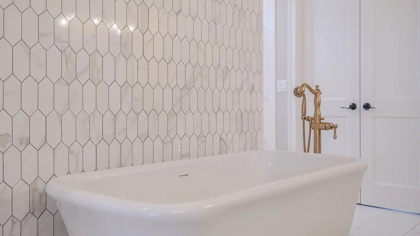 Lebanon luxury bathroom with freestanding white tub, brass fixtures, and marble-style hex tile accent wall in a Frazier Homes custom home, Ohio.