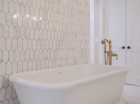 Lebanon luxury bathroom with freestanding white tub, brass fixtures, and marble-style hex tile accent wall in a Frazier Homes custom home, Ohio.