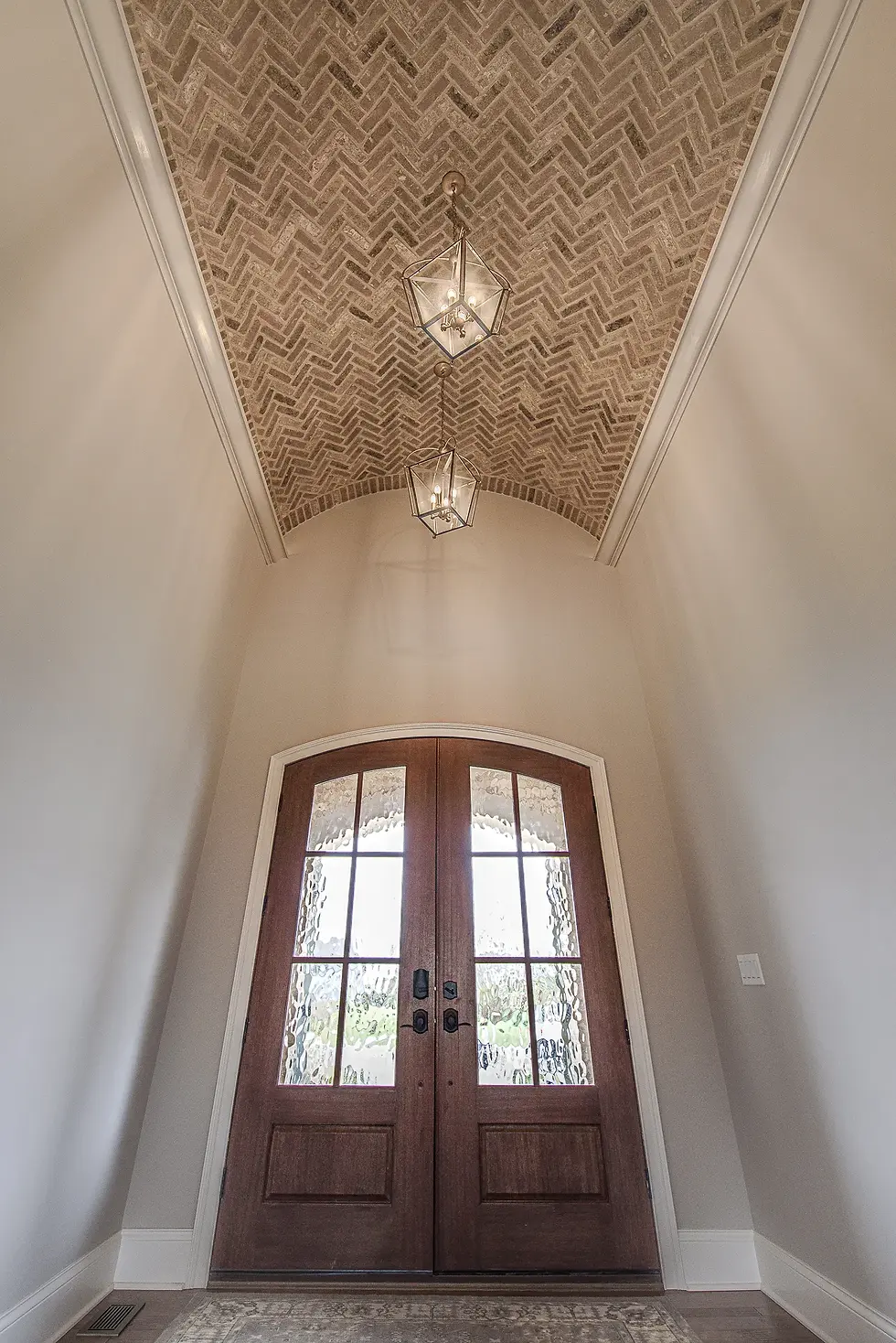 frazier-homes-custom-foyer-brick-barrel-ceiling-arched-doors.webp