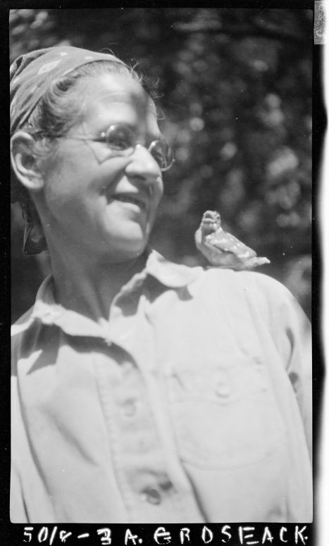 Old photograph of Ynés with a bandana on her head and a bird perched on her shoulder. She is smiling at the bird.