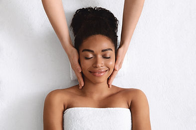 Top view of relaxed black young woman having facial massage over white background.jpg