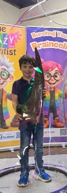 Child inside giant bubble with Triceratops brow horn at The Crazy Scientist science party.