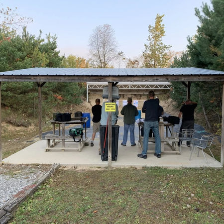 People practicing at a covered outdoor shooting range.