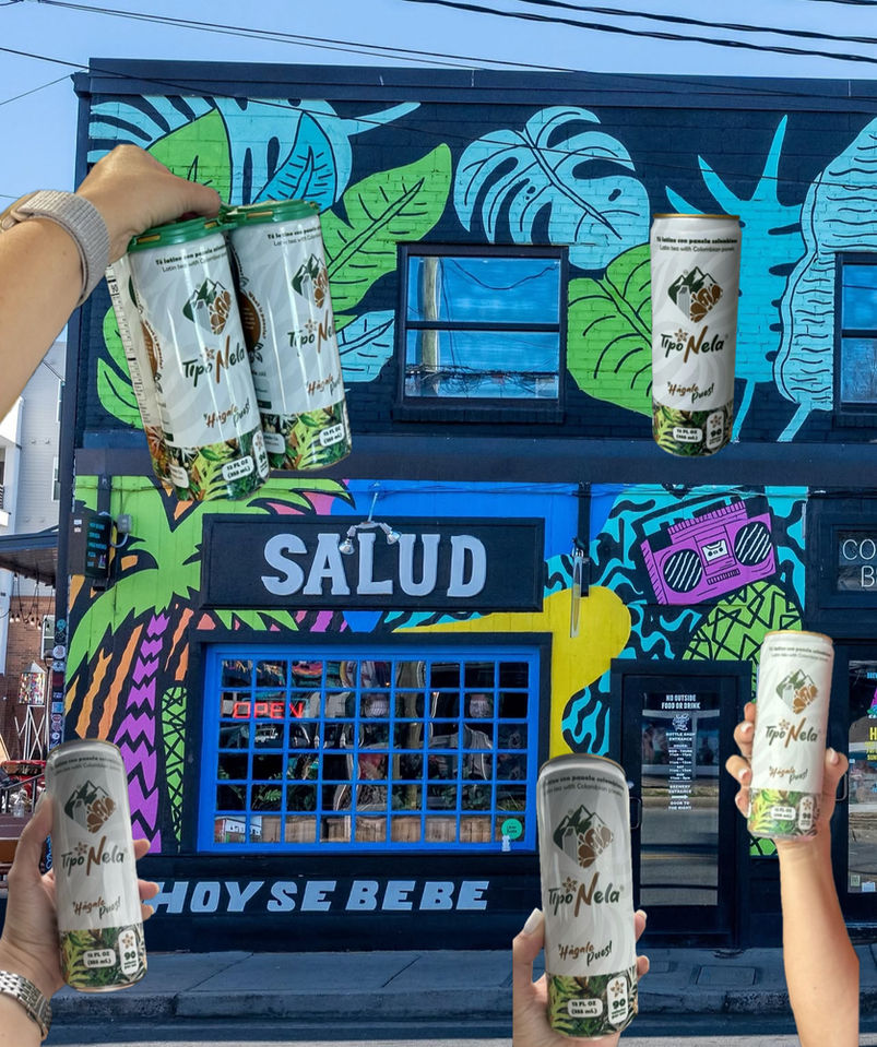 People holding Tipo Nela cans near a colorful display.