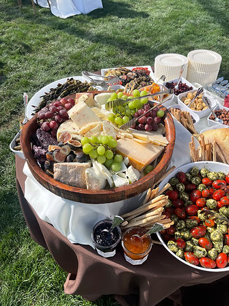 Platter of cheeses, grapes, and meats on an outdoor table