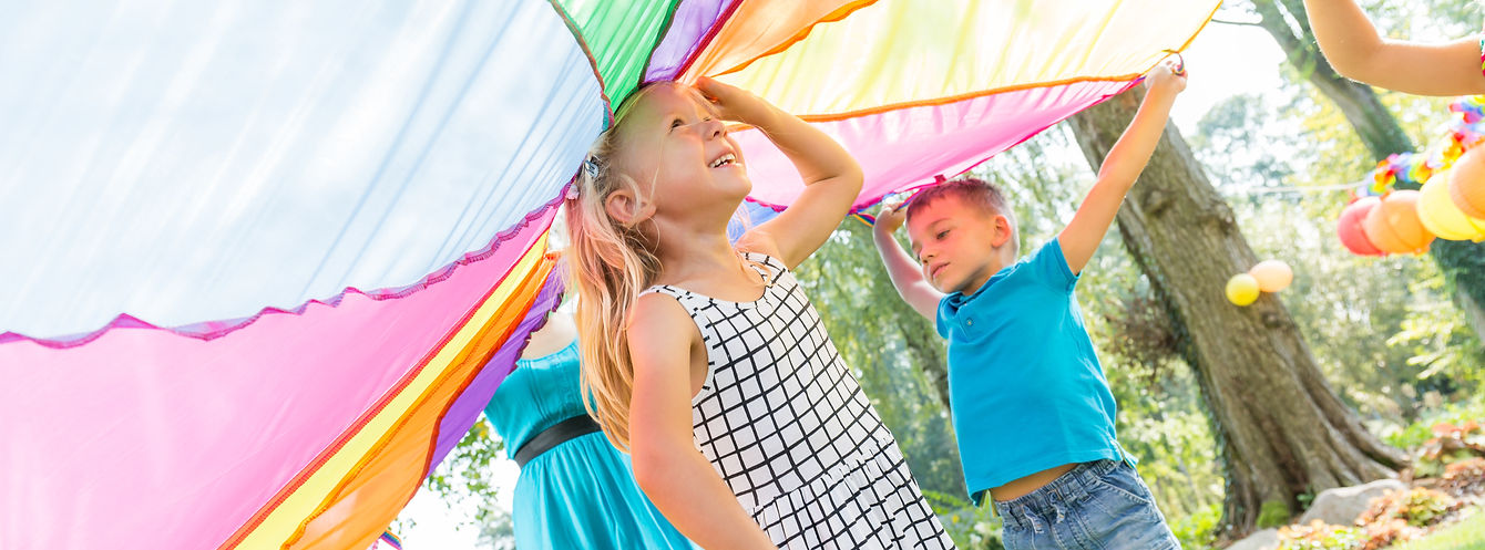 Children playing with colorful parachute outdoors
