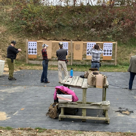 People practicing at an outdoor shooting range with targets.
