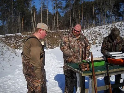 People at an outdoor snow-covered shooting range preparing.