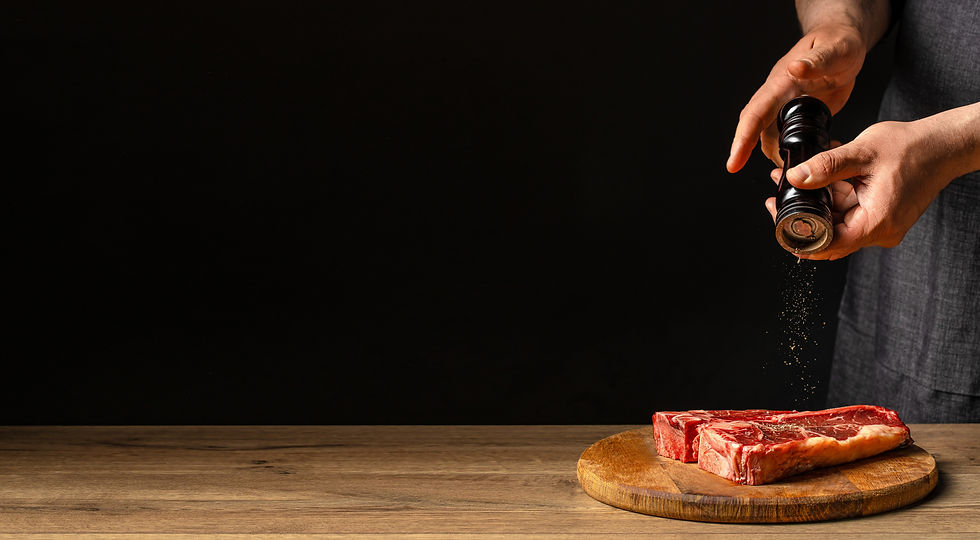 Chef grinding fresh black pepper over raw beef