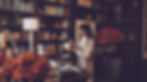 Woman in a cozy sweater redecorating a stunning home office, surrounded by shelves filled with books, autumn decor, and soft lighting.