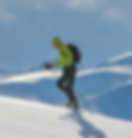 uomo con giacca verde fa ciaspole in salita
