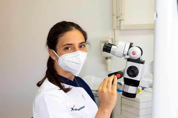 Médica dentista a usar o microscópio dentário para endodontia.