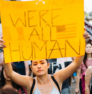 Protester with a sign that says "We're all human"