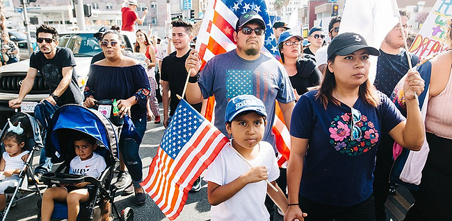 Family holding U.S. flags marching at a rally